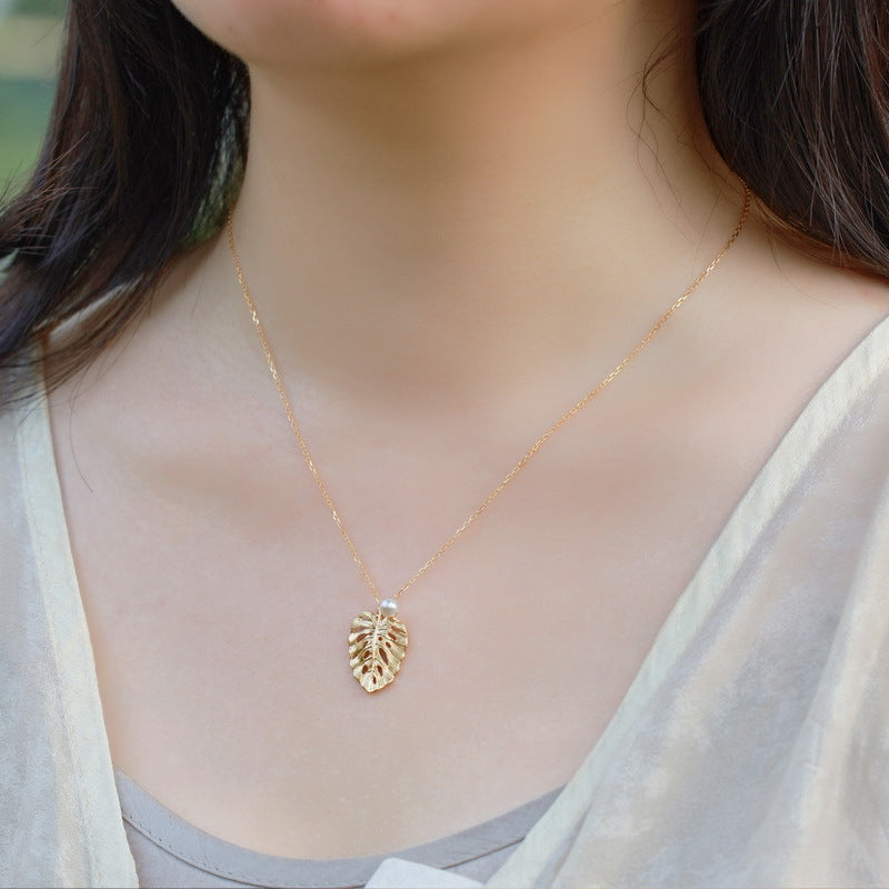 Woman wearing the VYLOREN brushed leaf pendant necklace