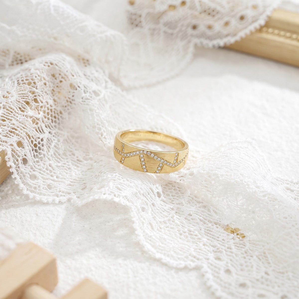 Wide gold-tone pave ring displayed on white lace