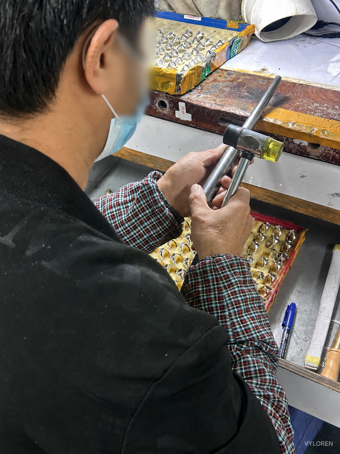 A craftsperson shaping a jewelry piece at a workbench
